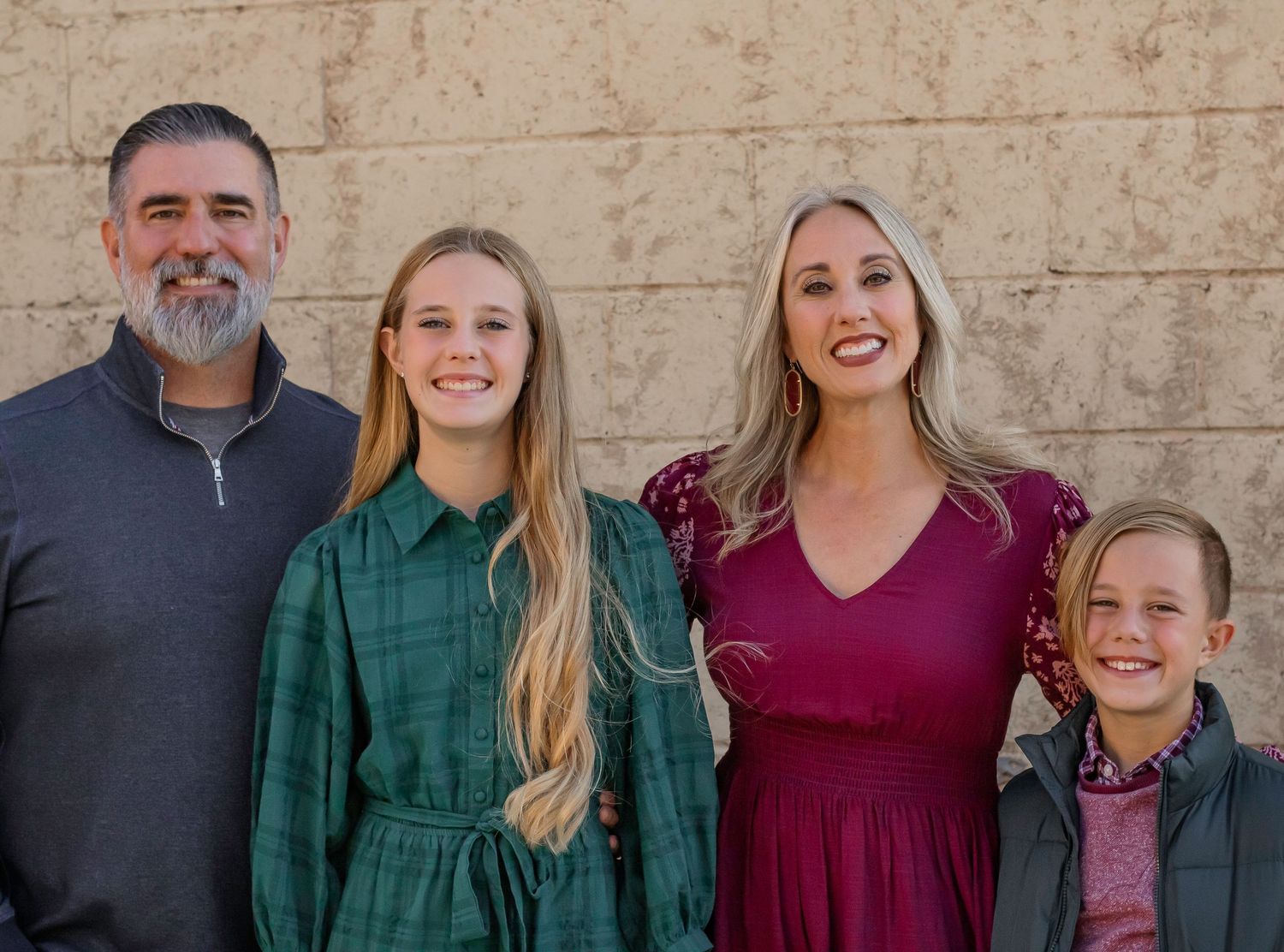 Family portrait group photo against a neutral stone wall background.