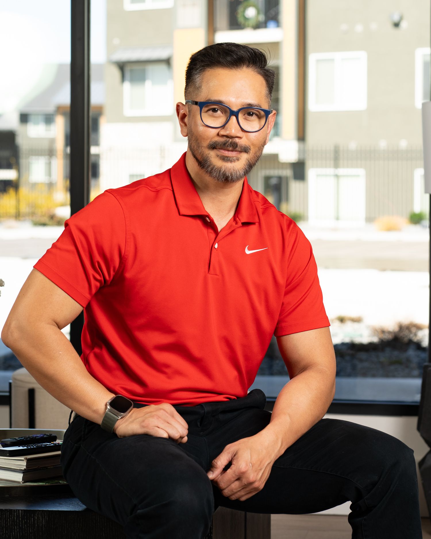 Man posing for his headshot with a red shirt and glasses on. Positive and professional headshots taken in Cache Valley studio.