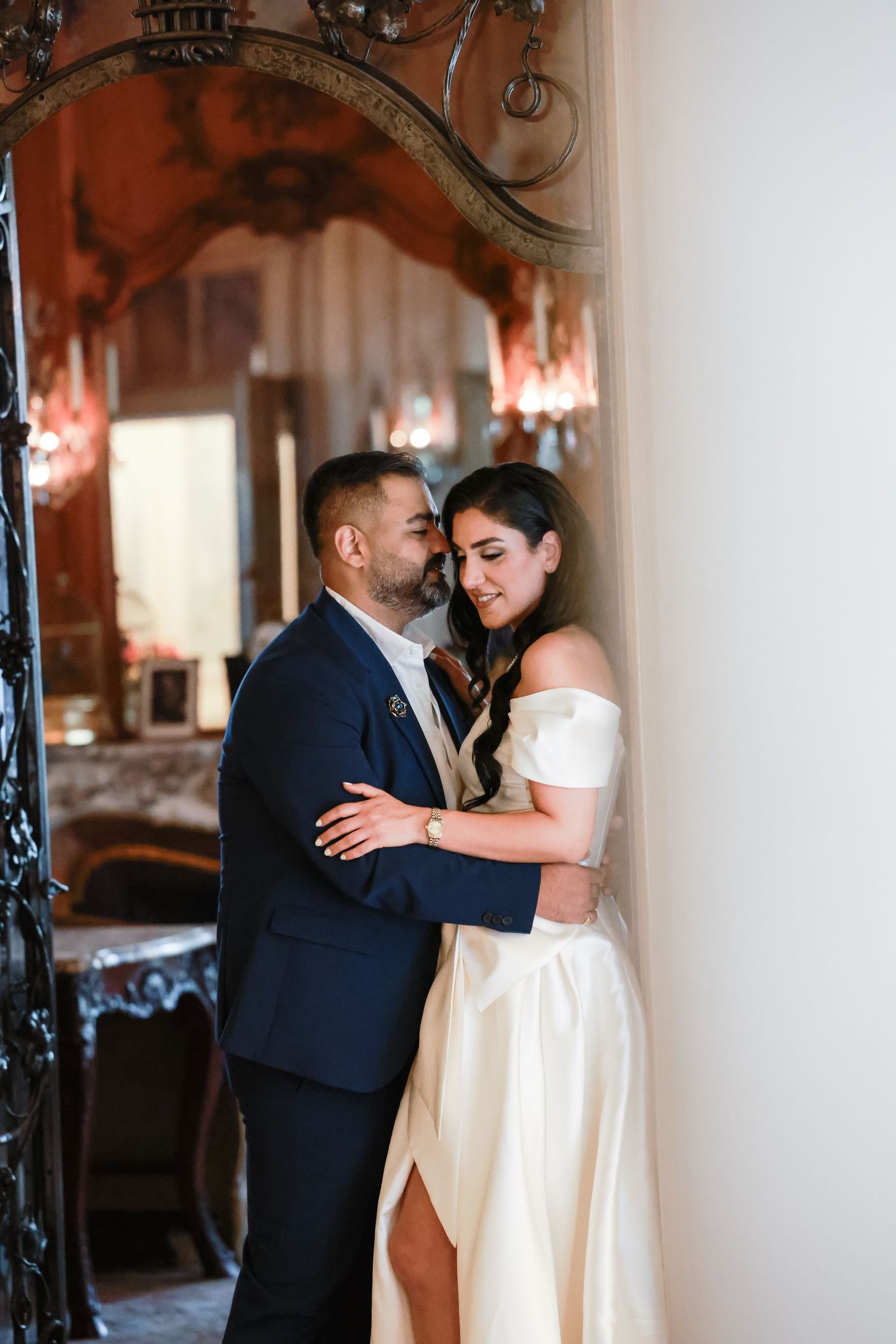 Romantic moment between couple in formal attire against ornate mirror.