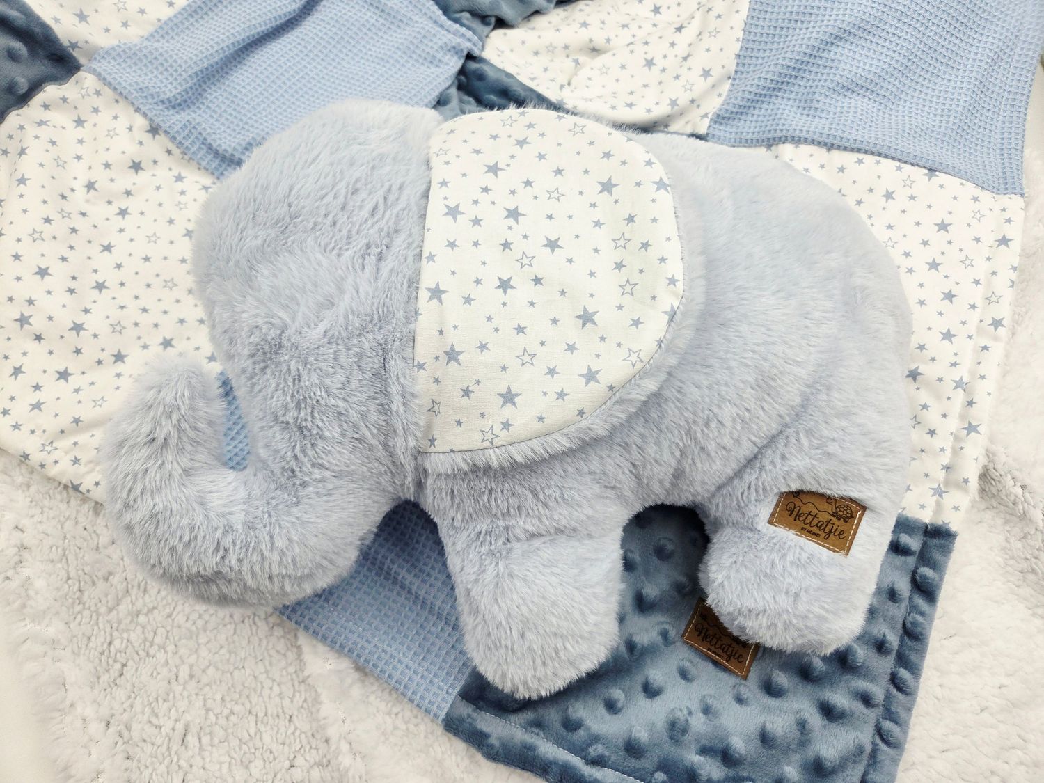 Soft gray plush elephant on a blue and white dotted minky blanket.