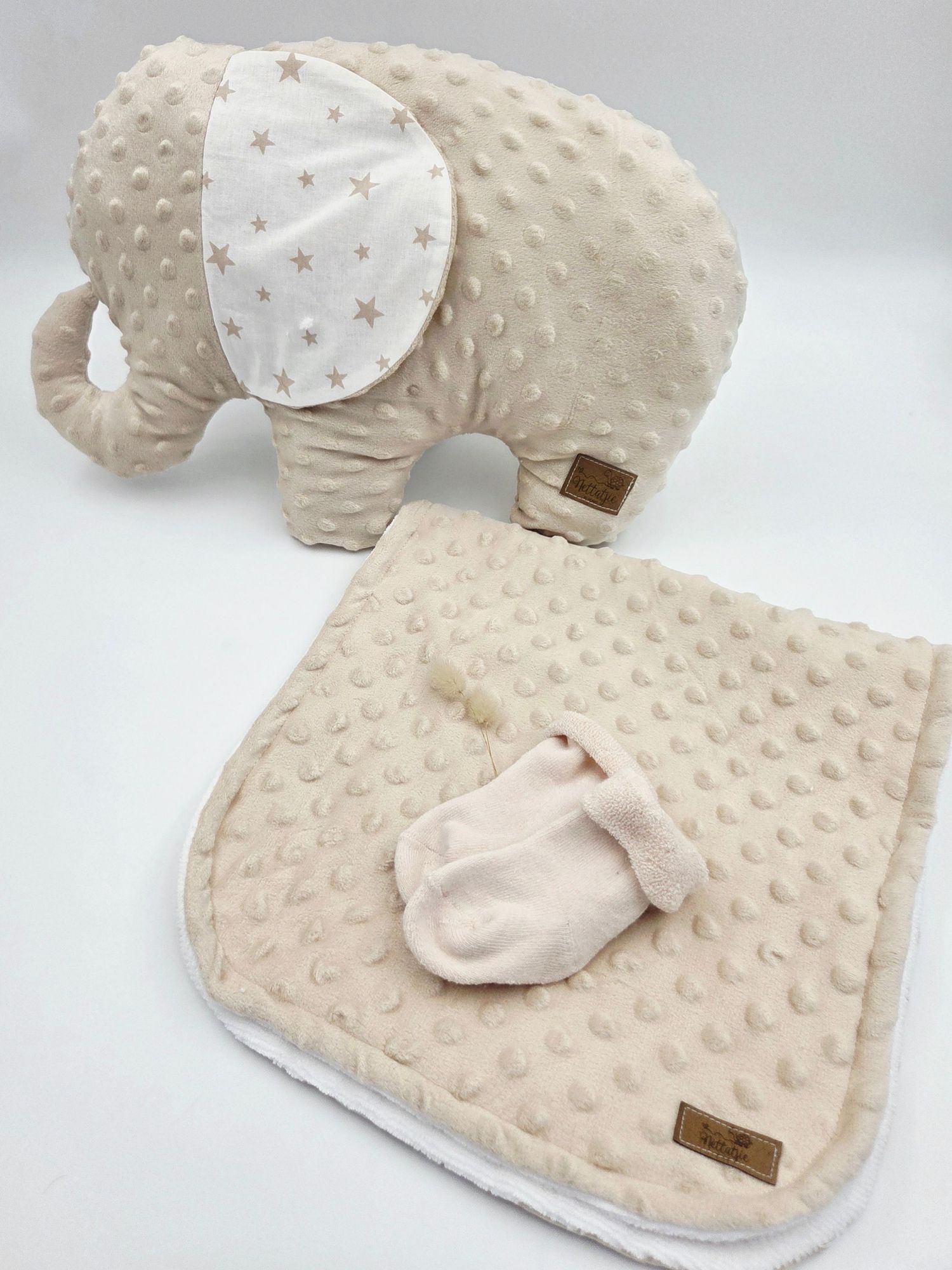 Cream minky dot elephant plush toy with star-patterned ears and matching textured blanket.