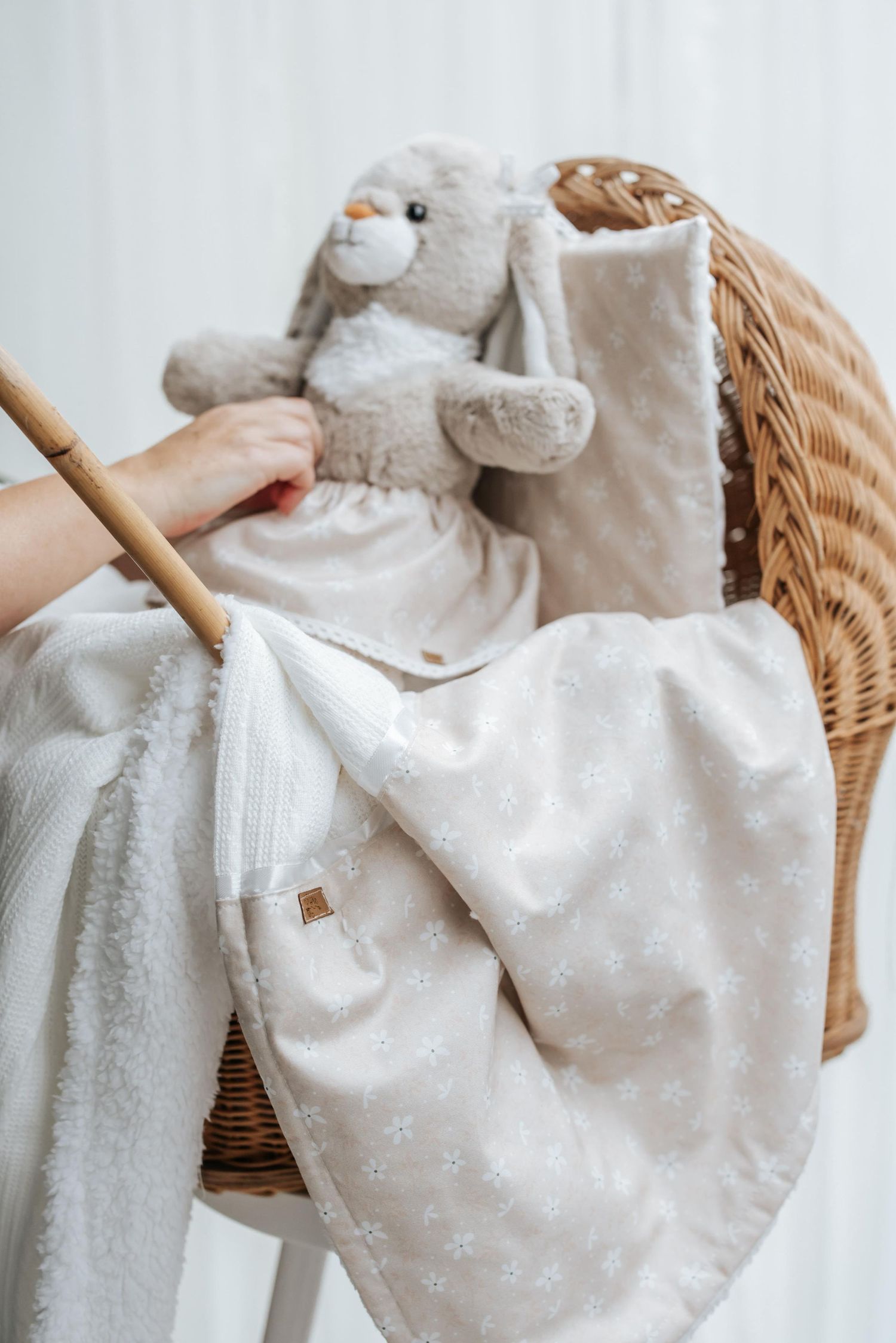 White plush lamb toy with polka dot blanket draped over wicker basket.