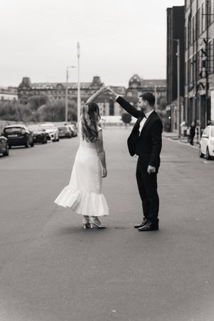 A bride and groom stand apart on a city street in black and white, creating a romantic and artistic composition.