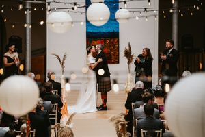 Indoor wedding ceremony with string lights and white lanterns.