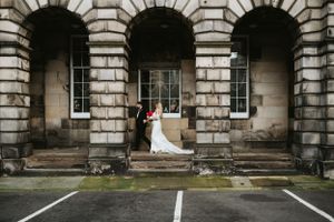 A wedding couple walks through arches in Edinburgh City centre