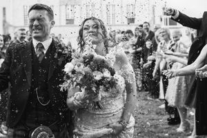 Wedding guests shower newlyweds with confetti and flower petals in black and white celebration photos.