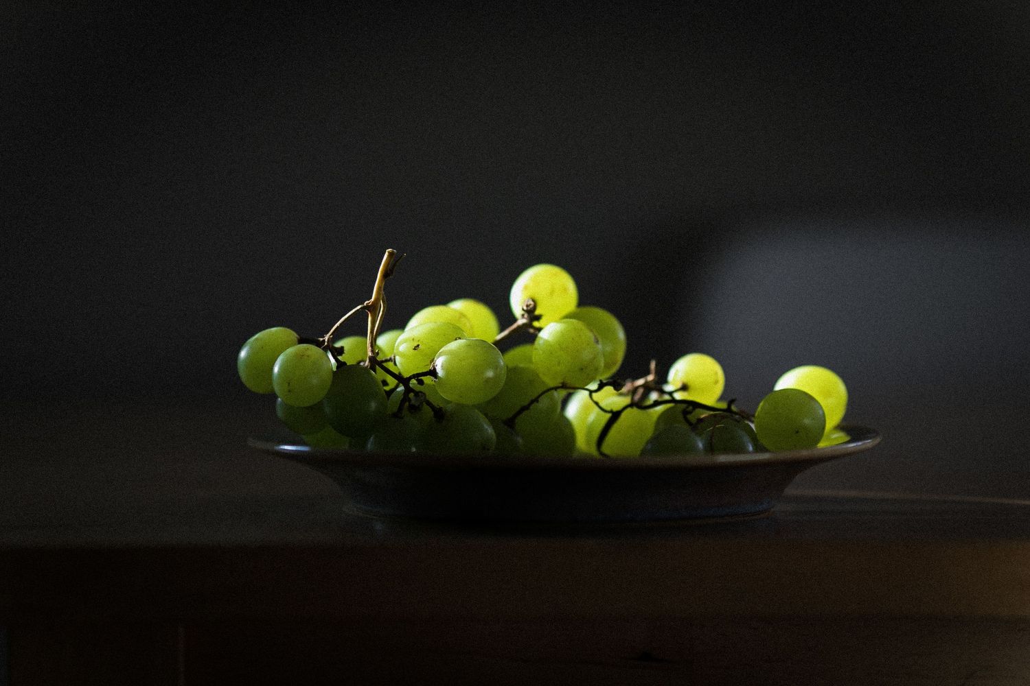 Fresh green grapes arranged in dramatic low-key lighting.