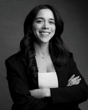 Black and white portrait of woman in business attire with crossed arms.