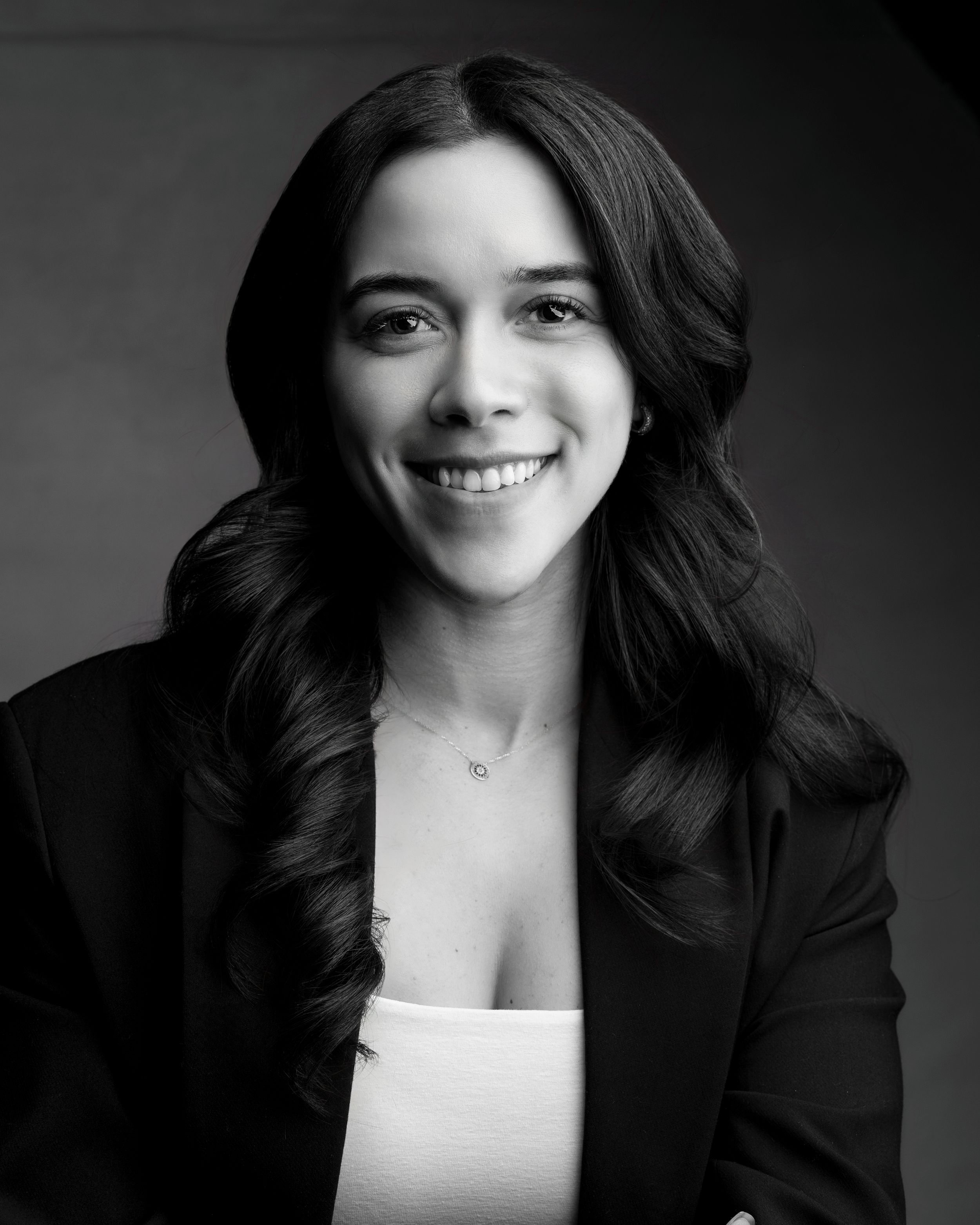 Professional black and white headshot featuring elegant business attire and natural smile.