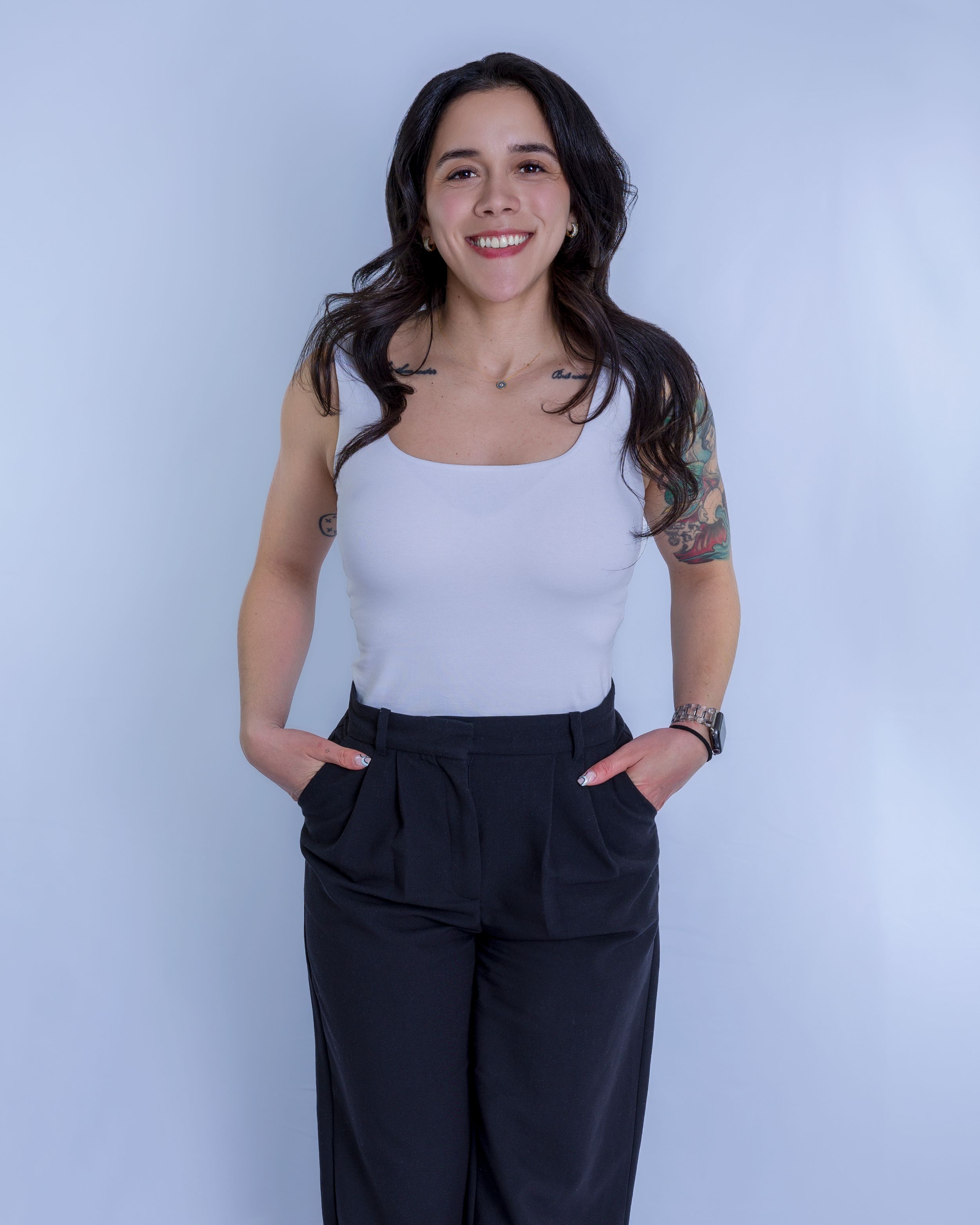 Professional portrait featuring a business casual outfit with a white tank top and dark high-waisted pants.