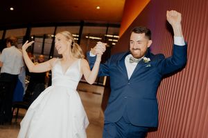 A couple dances together at their wedding reception, with the bride in white and groom in navy suit.