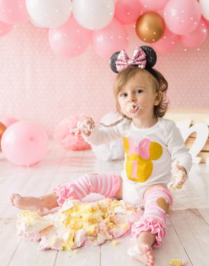 Festive pink and white balloon party setup with Mickey Mouse decorations and cake smash celebration.