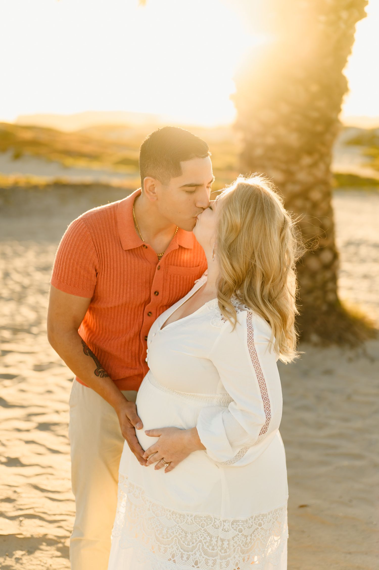 husband and wife kiss during their sunset beach maternity photoshoot at Ventura beach by Ojai photographer