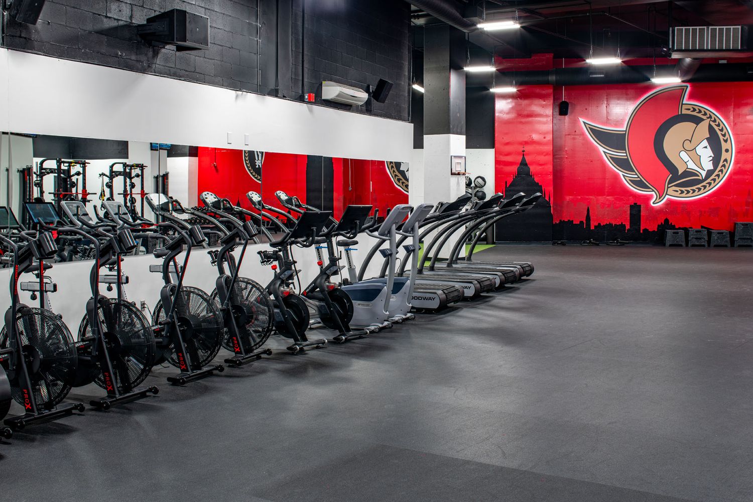 Commercial interior photography of a professional team gym, showing rhythmic placement of fitness equipment and branded wall graphics