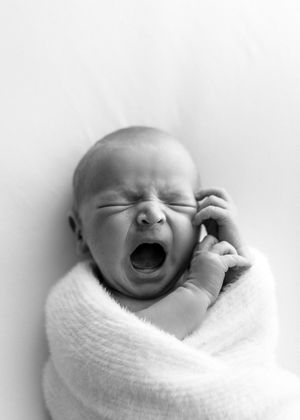 A sleeping newborn baby swaddled in white blanket shown in three close-up photographs.