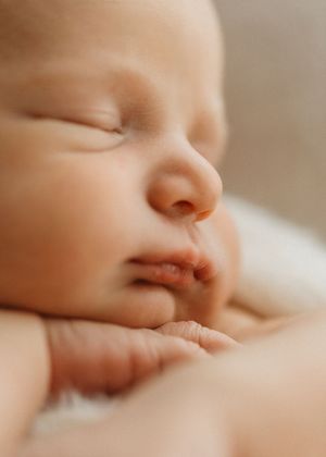 Close-up view of a sleeping infant's face with peaceful expression in soft lighting.