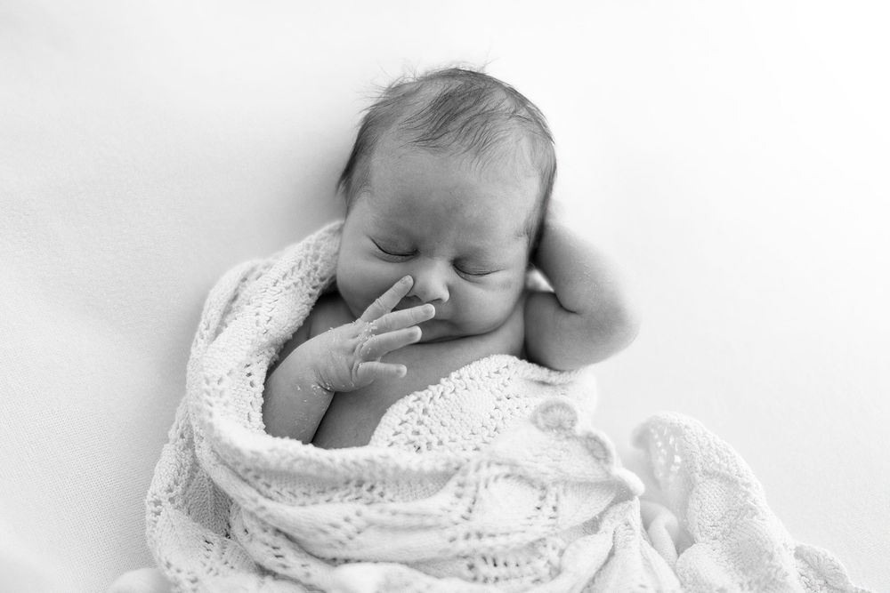 A baby in white clothing sleeping peacefully across multiple photos in a dreamy collage formation.