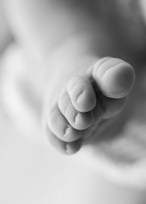 Close-up black and white photograph of tiny baby toes against a soft blurred background.