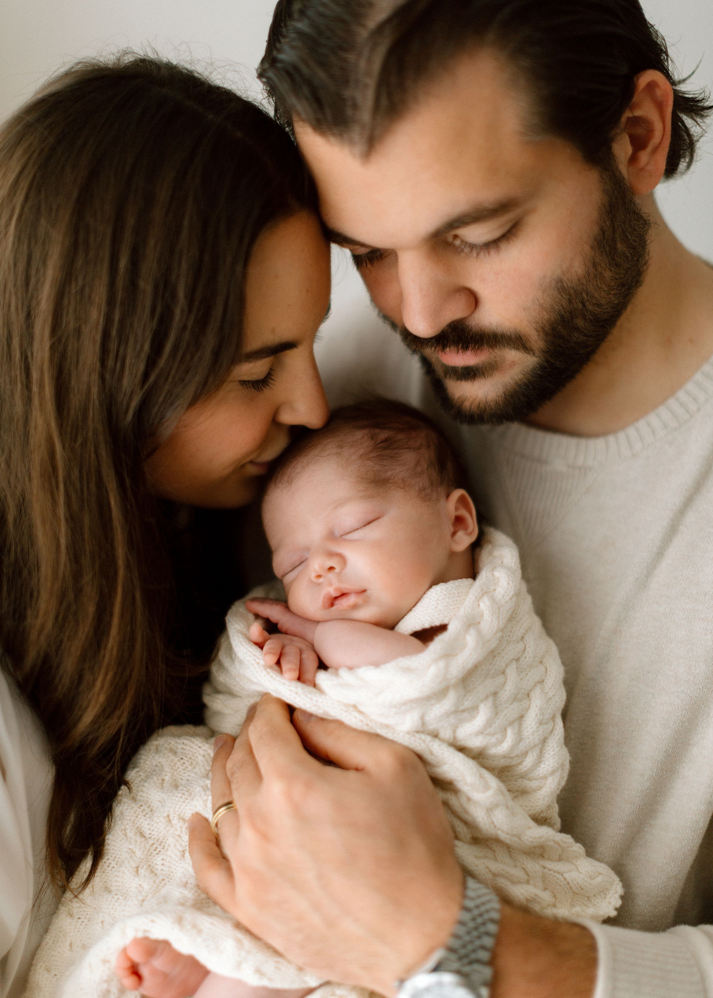 Parents sharing tender moments with their baby in a series of intimate black and white family portraits.