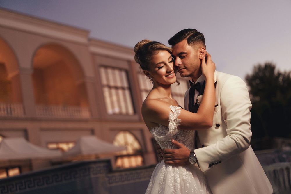 Elegant wedding couple shares romantic moments at sunset in front of a grand building.
