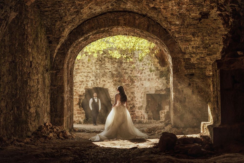 A series of stone archways in an ancient tunnel or crypt with natural light filtering through openings.