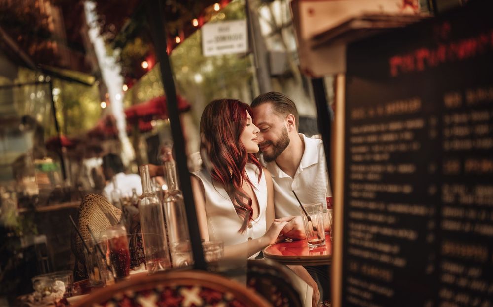 Romantic couple sharing intimate moments at a cozy restaurant bar with warm ambient lighting and wine glasses.
