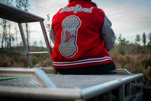 A red varsity jacket with logo details sits on display outdoors on a cloudy day.