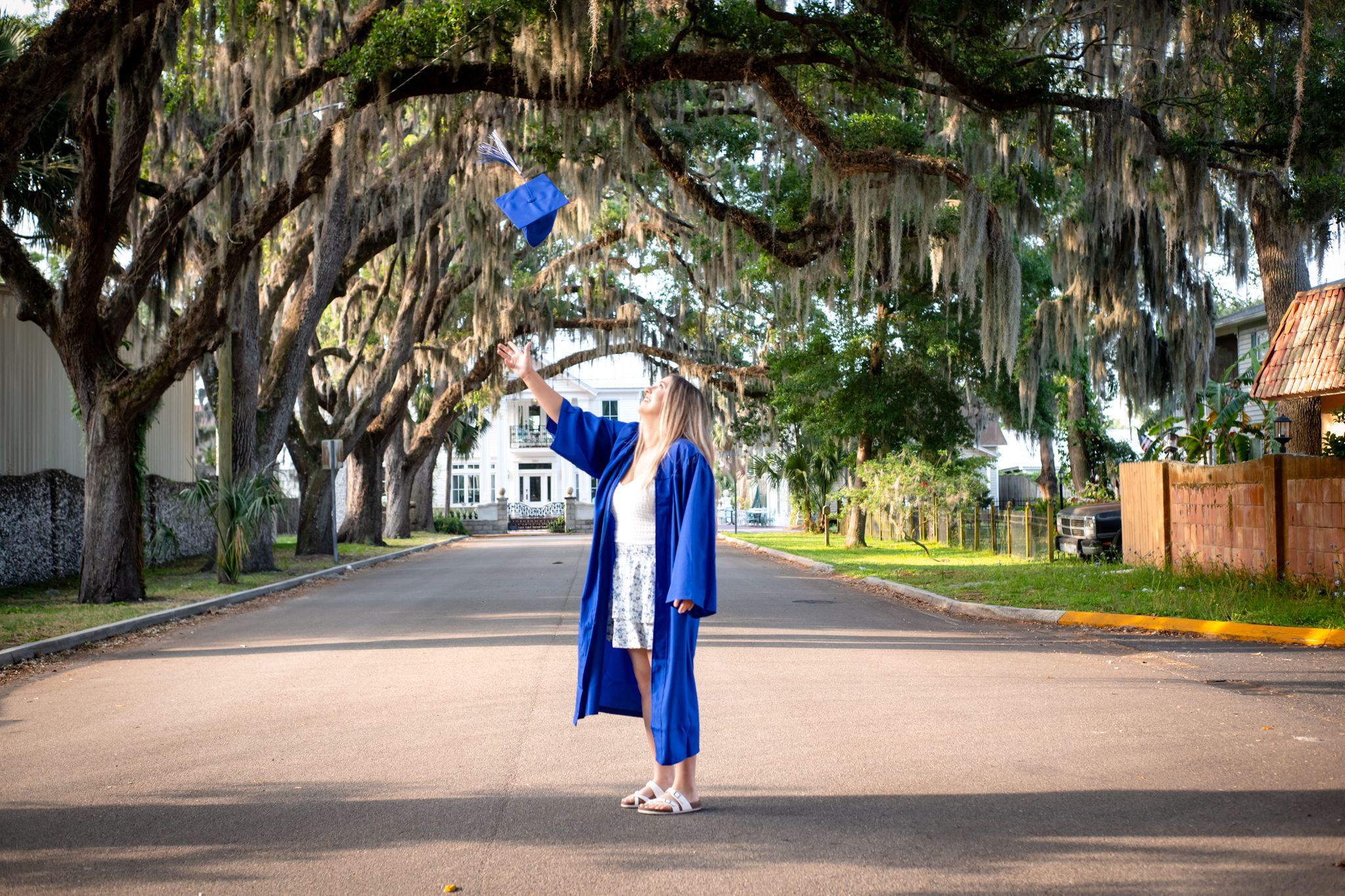 A graduation photo taken on a tree-lined street with Spanish moss hanging overhead.
