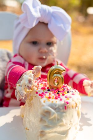 A small cake decorated with sprinkles and a number 6 candle sits on a white table.