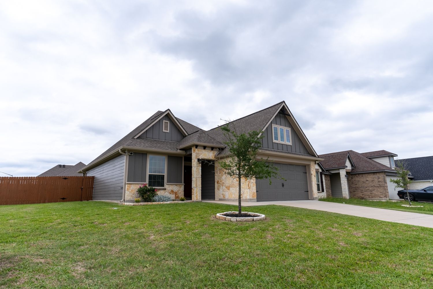 Single-story suburban house with gray exterior and attached garage on a grassy lot.