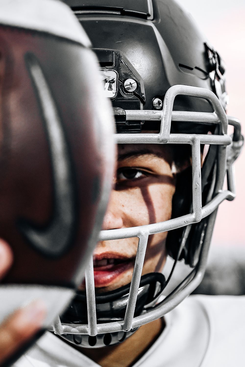 Close-up shot of football player through helmet face mask in dramatic lighting.