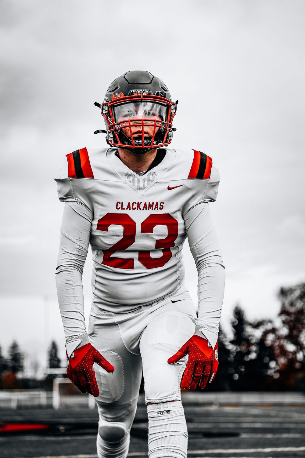 Football player in white Clackamas jersey number 23 on field.