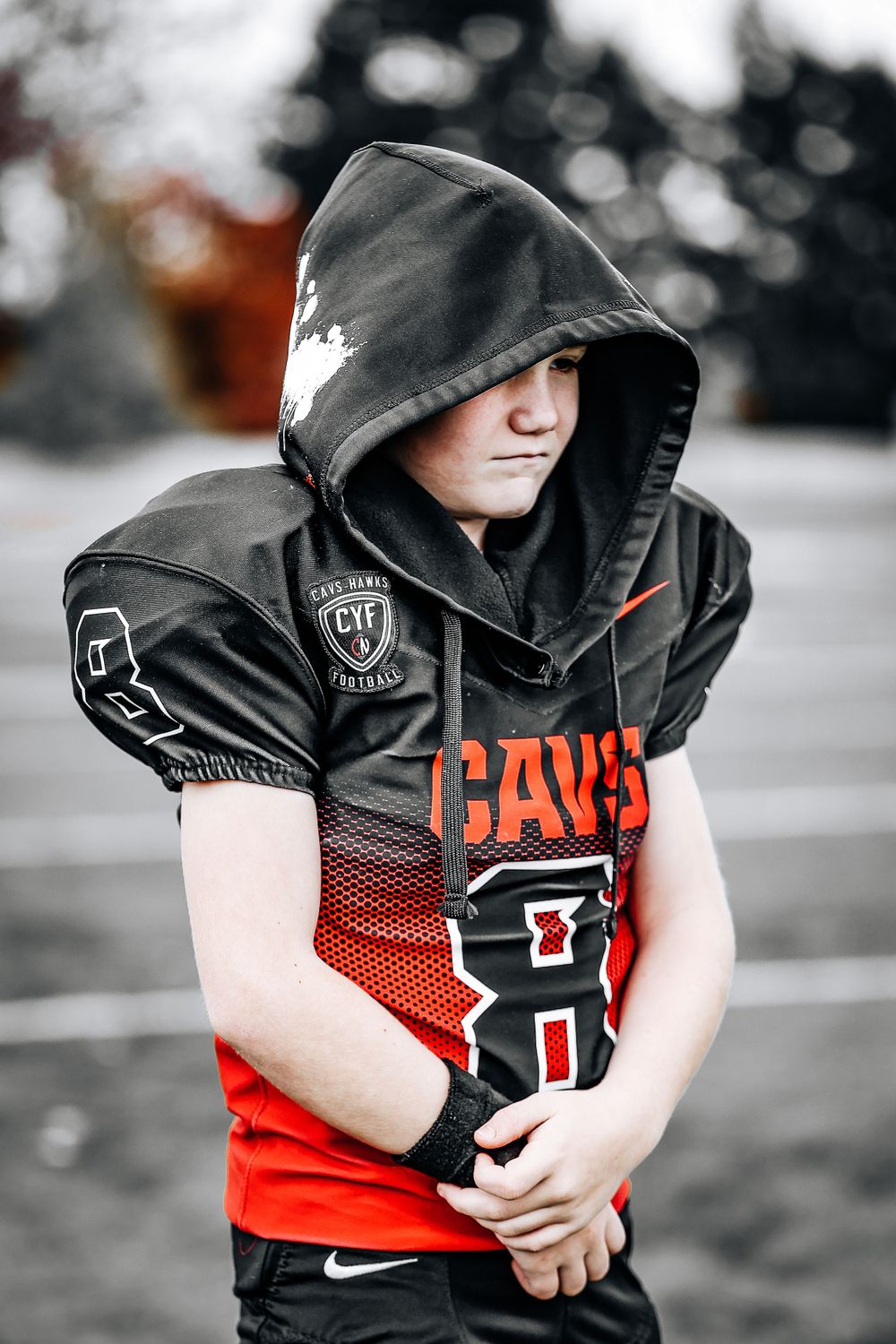 Football player in black and red Cavs hoodie with team logo.