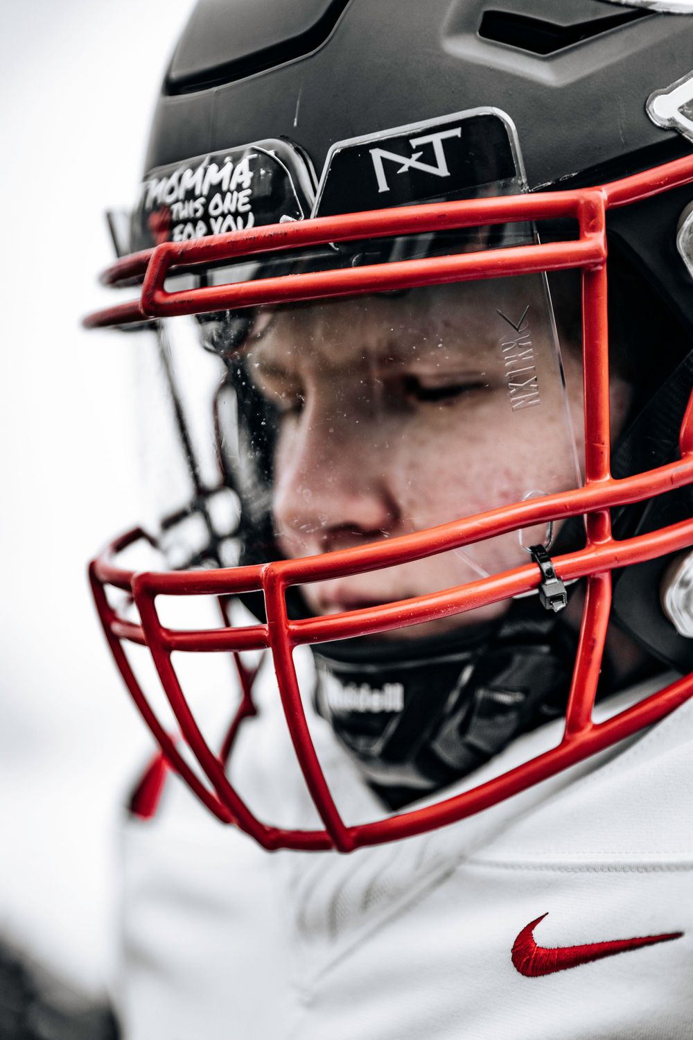 Close-up of football helmet with red facemask against white background.