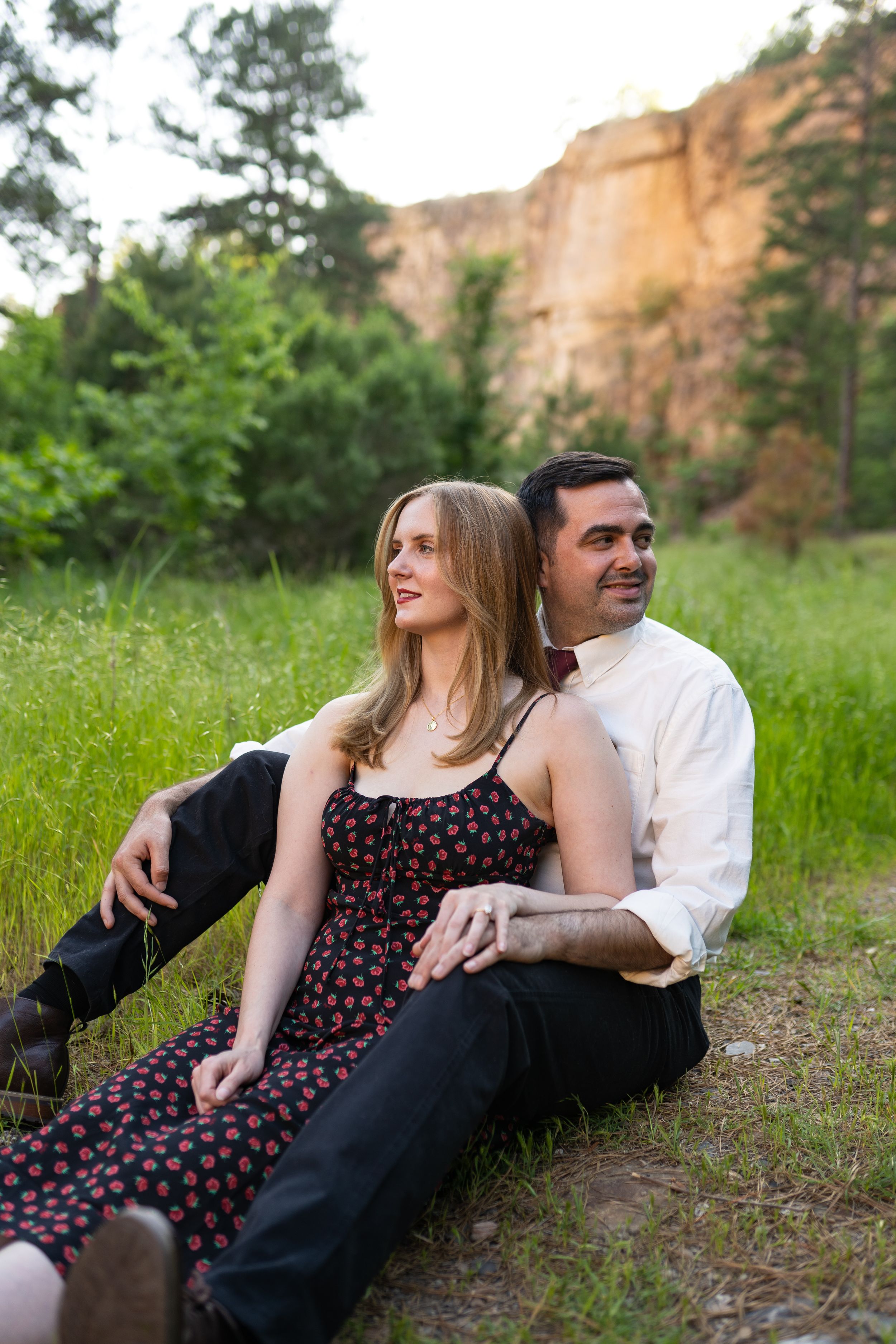 Couple relaxes together on ground in scenic mountain meadow during golden hour.