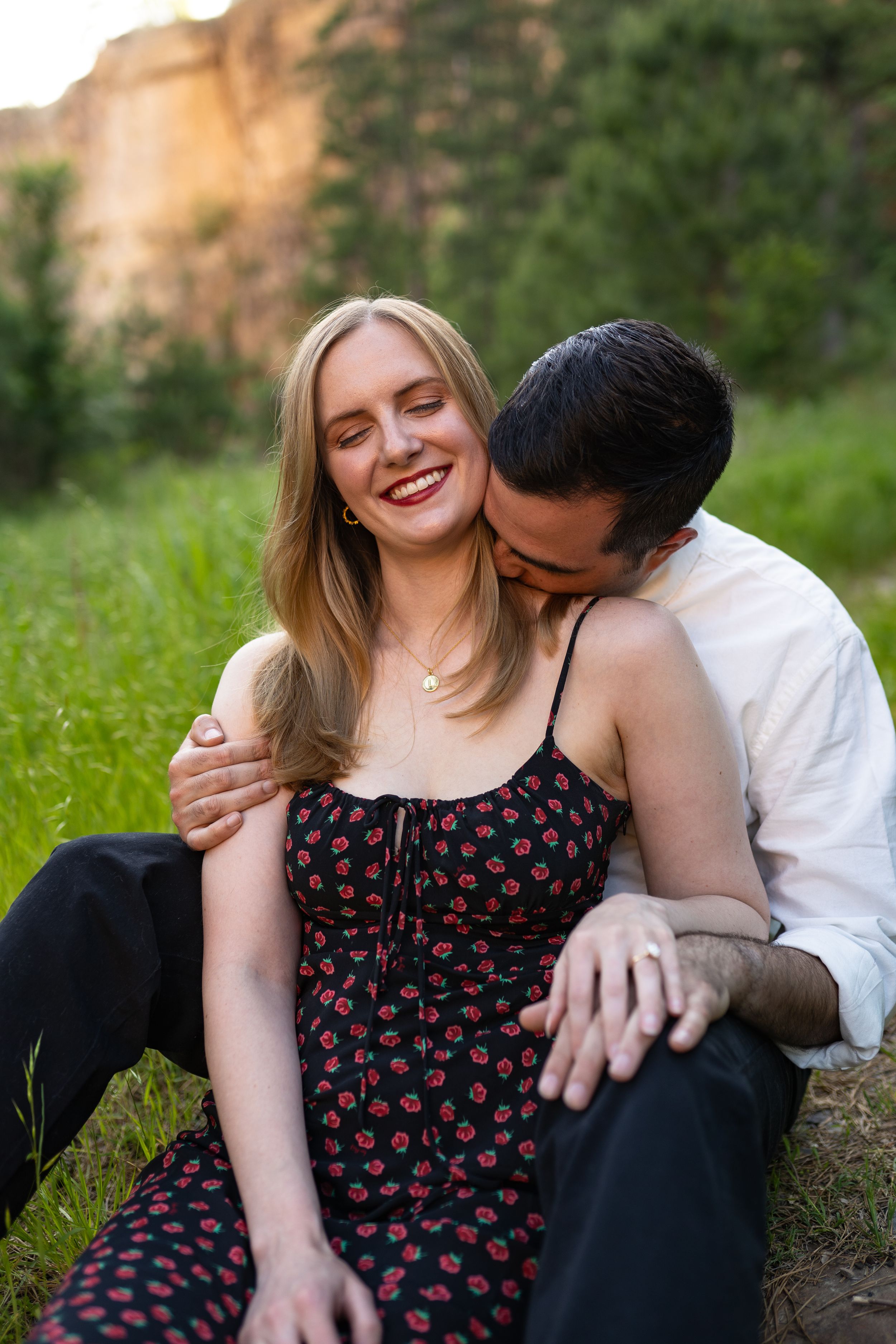 Intimate couple moment captured in sunlit meadow with woman in polka dot dress.