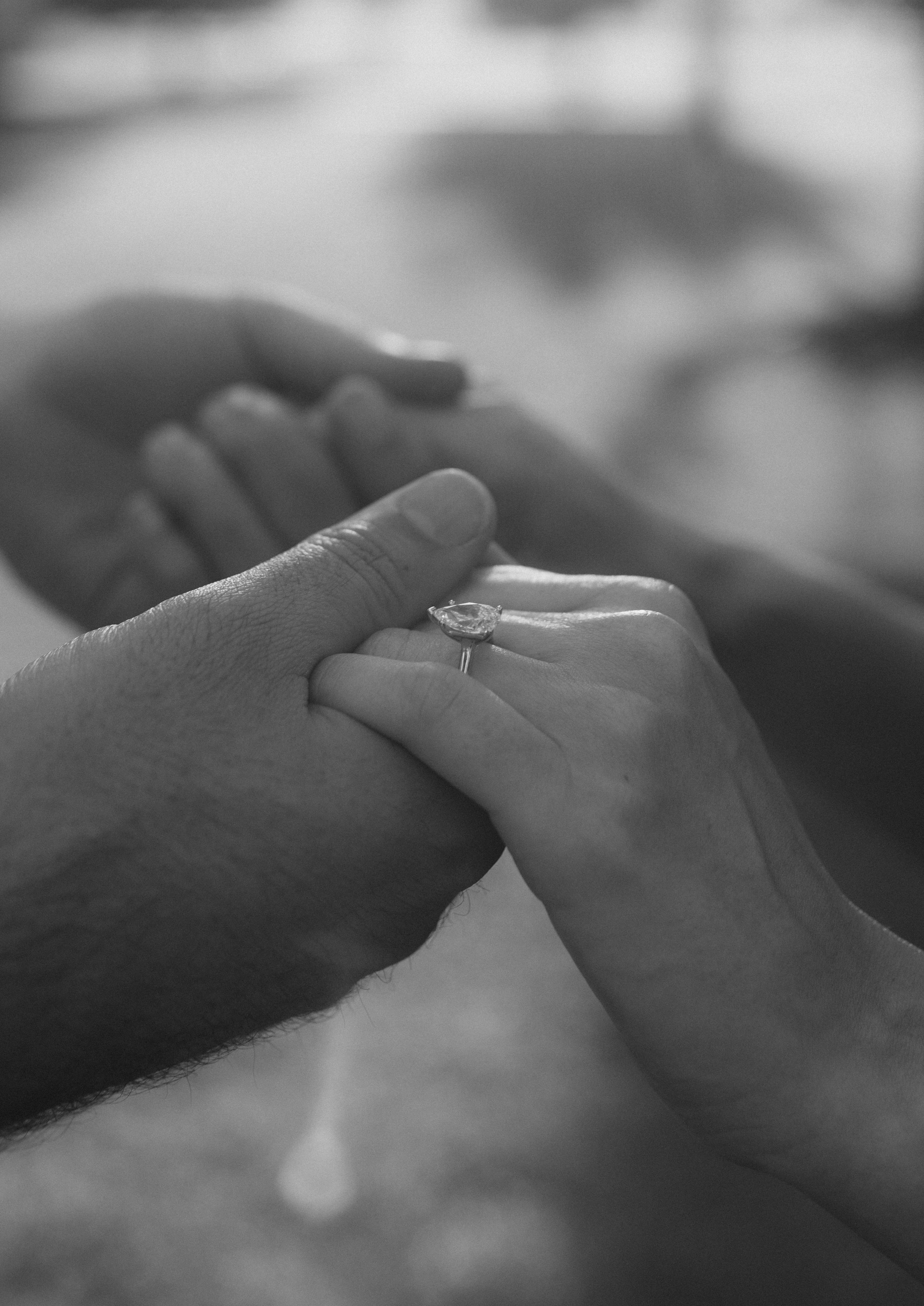 Close up black and white photo of hands with engagement ring.