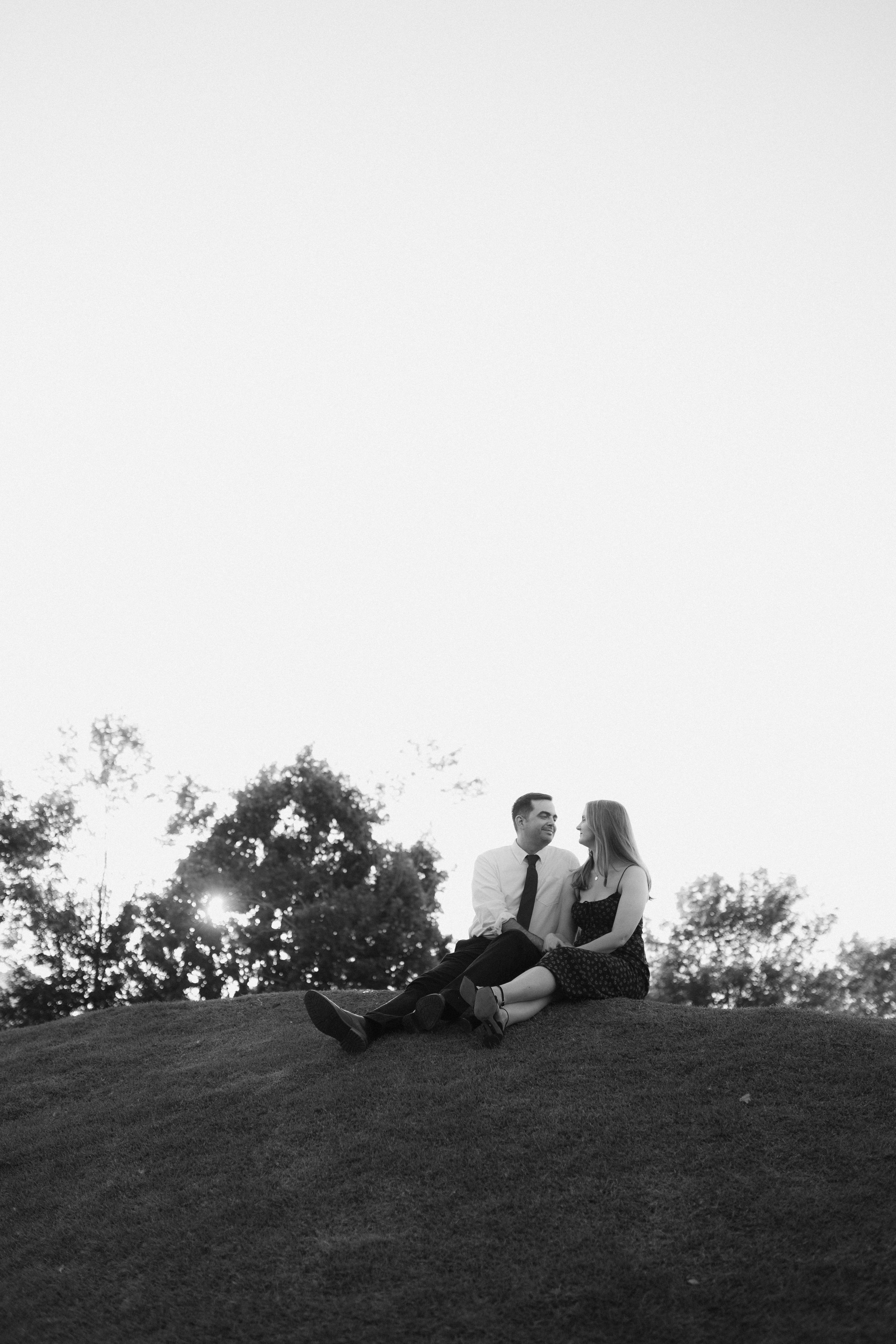 Silhouetted couple laying on hillside in dramatic black and white composition.