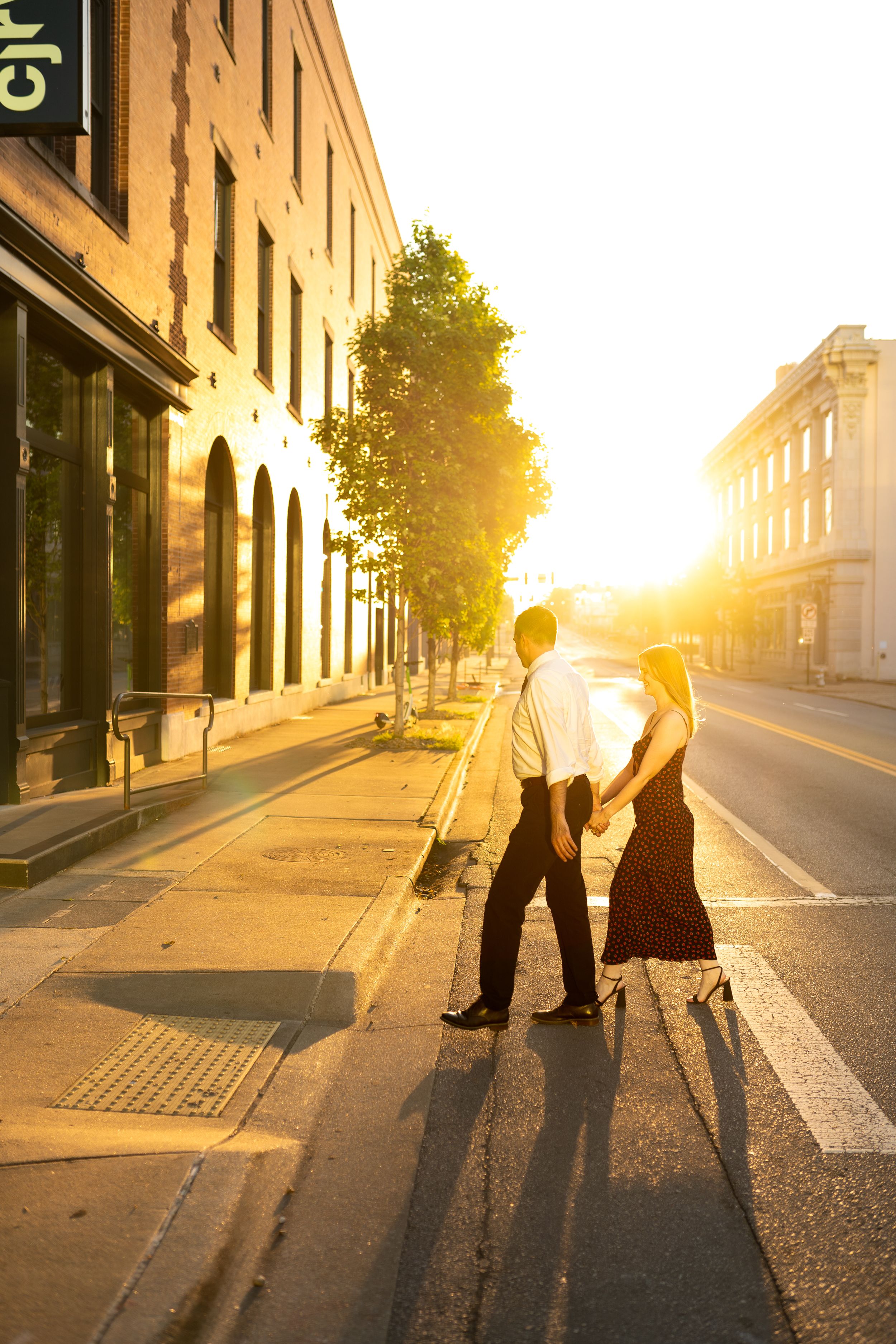 Couple's silhouettes against golden sunset on urban street with long shadows.