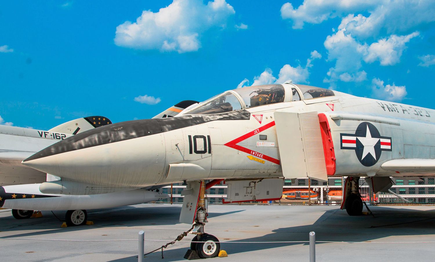 A vintage US Navy F-4 Phantom fighter jet with number 101 displayed on static display against a blue sky.