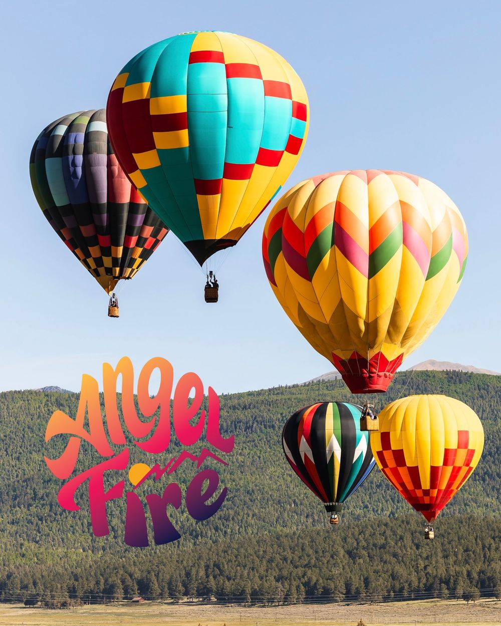 Colorful hot air balloons soar over Angel Fire, New Mexico, with vibrant geometric patterns against a clear blue sky.
