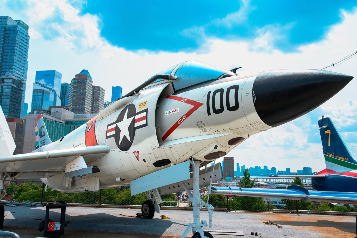 A white US Navy RA-5C Vigilante aircraft with number 100 displayed against an urban skyline.