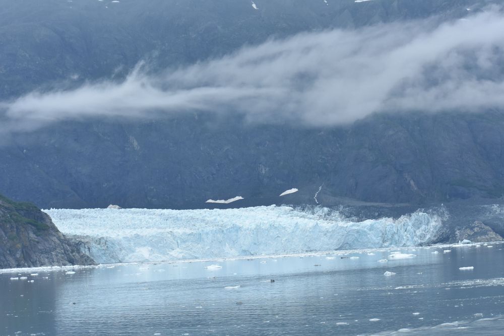 Massive glacier in Alaska with misty mountains in the background.