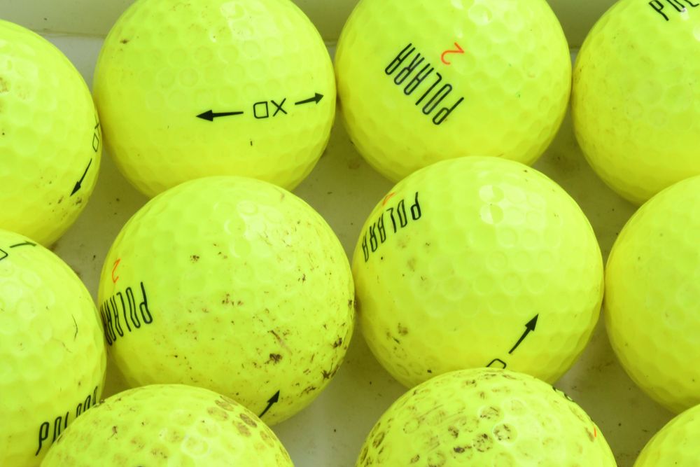 Close-up of bright yellow tennis balls with directional arrows arranged in rows.