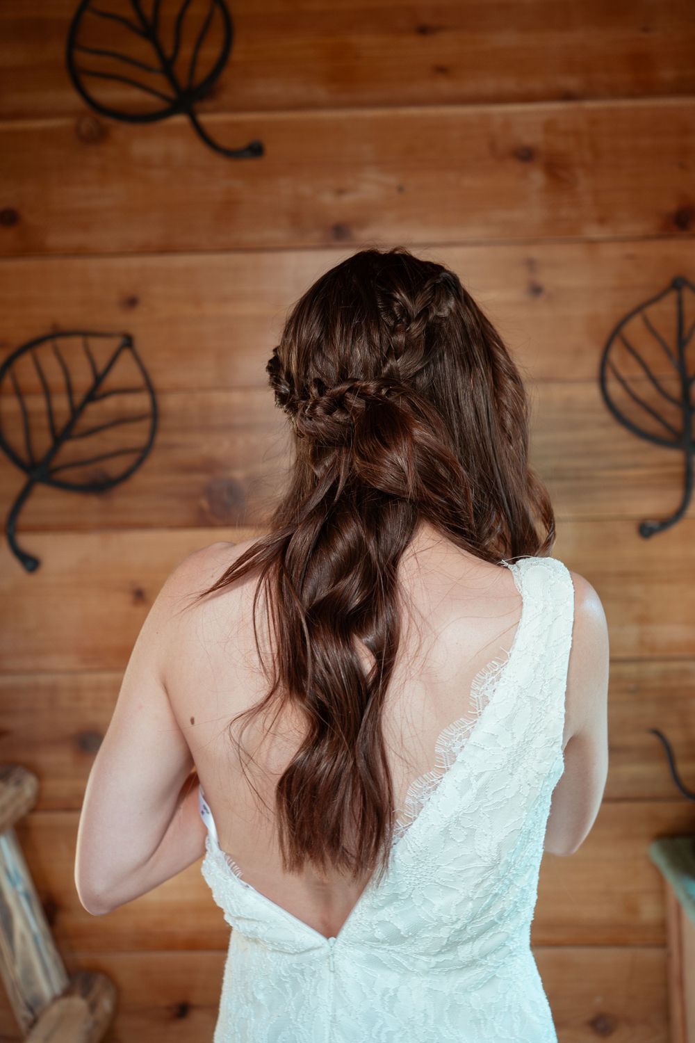 Back view of bride showing intricate braided hairstyle and lace dress with open back.