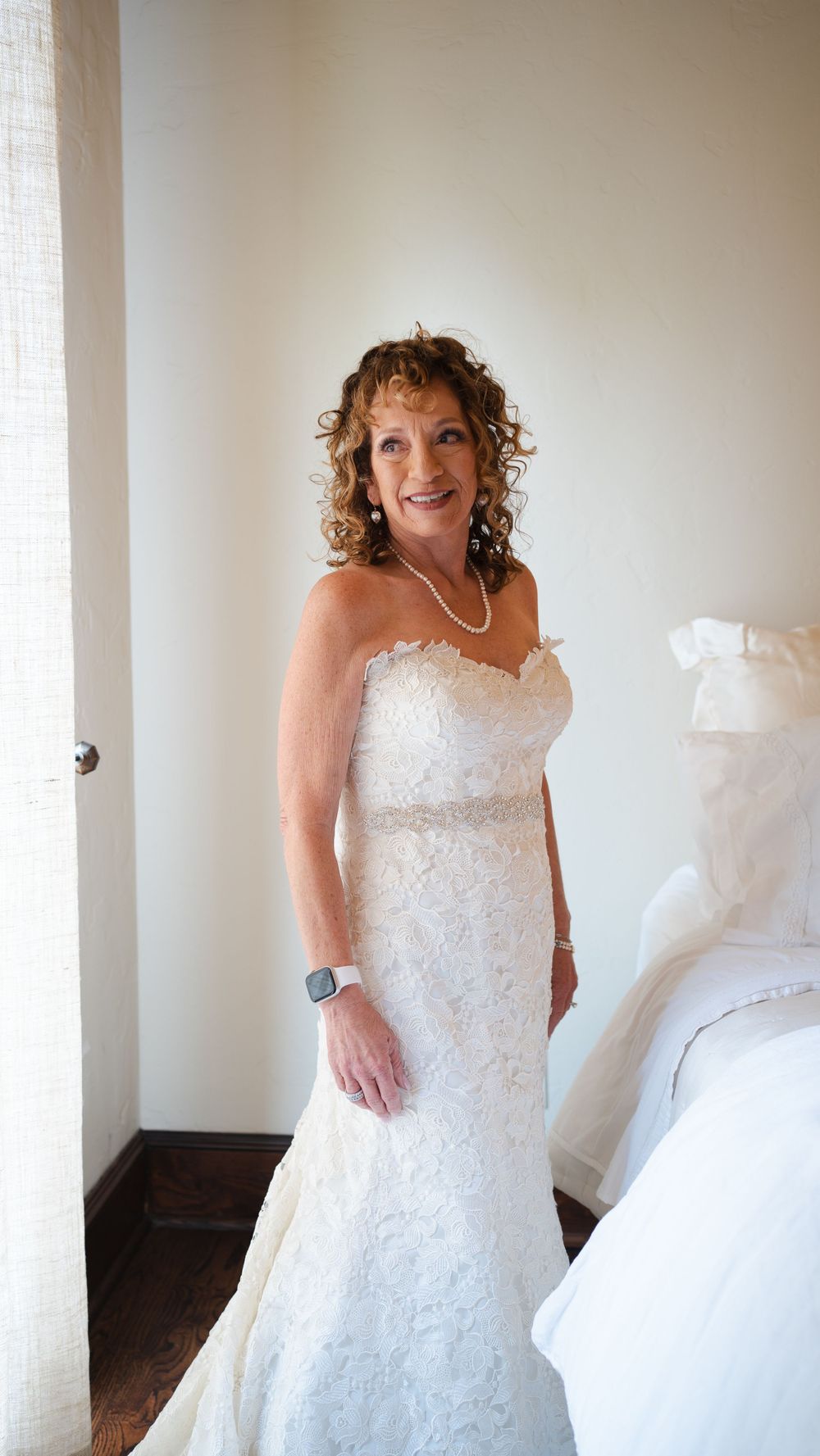 Bride wearing a beautiful lace wedding gown posing in a simple room.