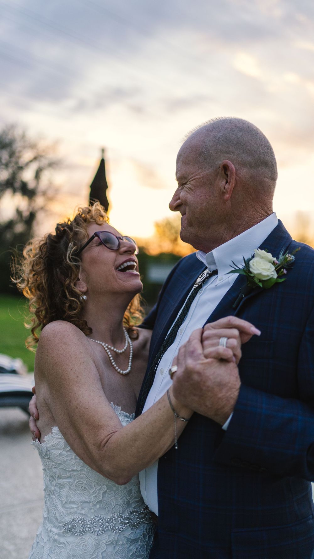 Happy couple sharing an intimate dance moment at sunset during their wedding celebration.