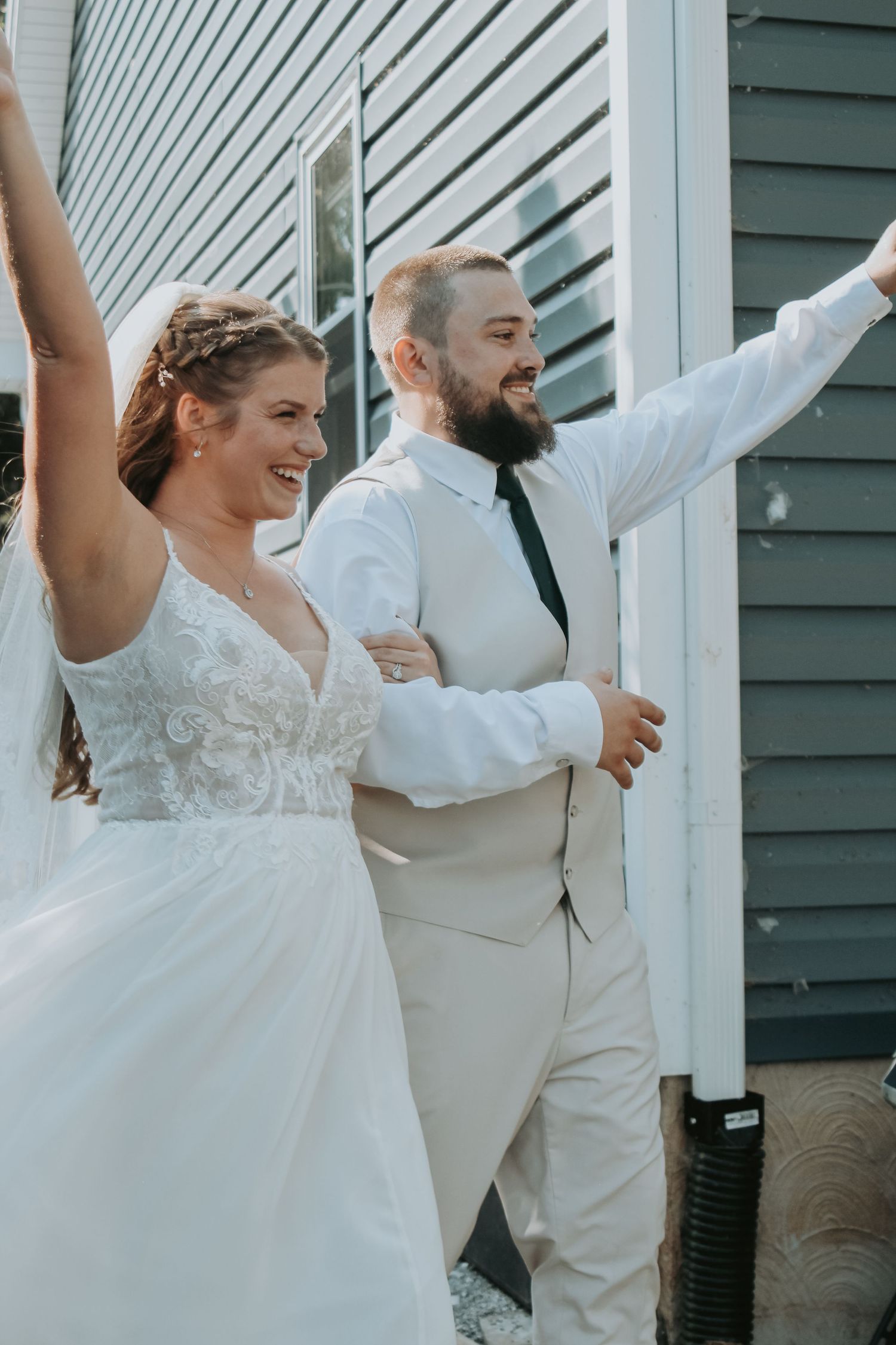 Newlyweds celebrate with arms raised outside after wedding ceremony.