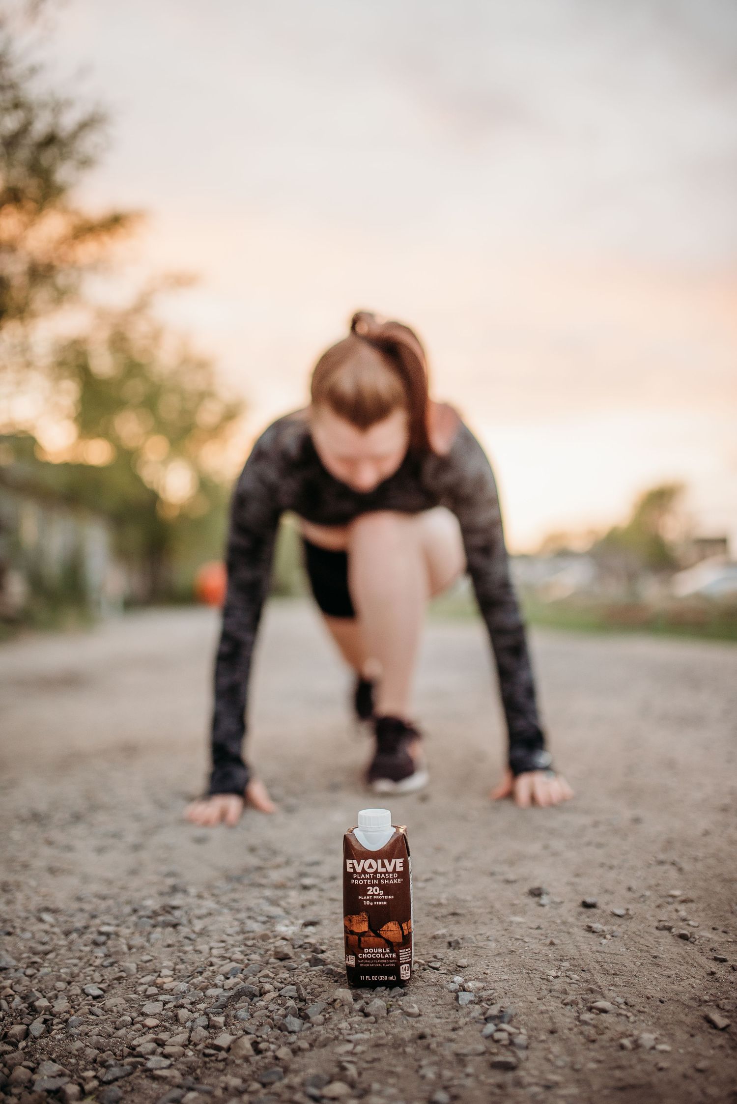 Athletic figure in starting position on dirt road with cold brew coffee bottle.