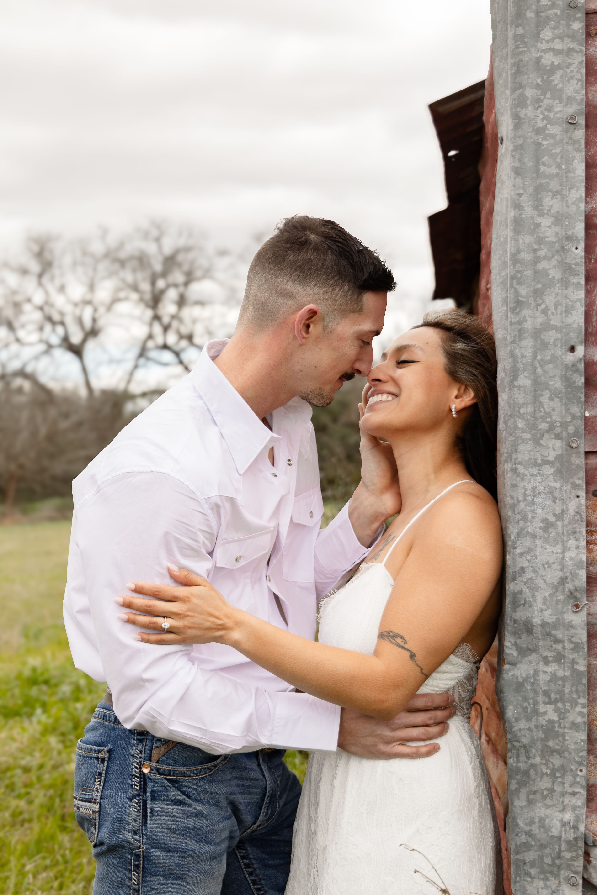 Engaged couple about to kiss next to a barn.